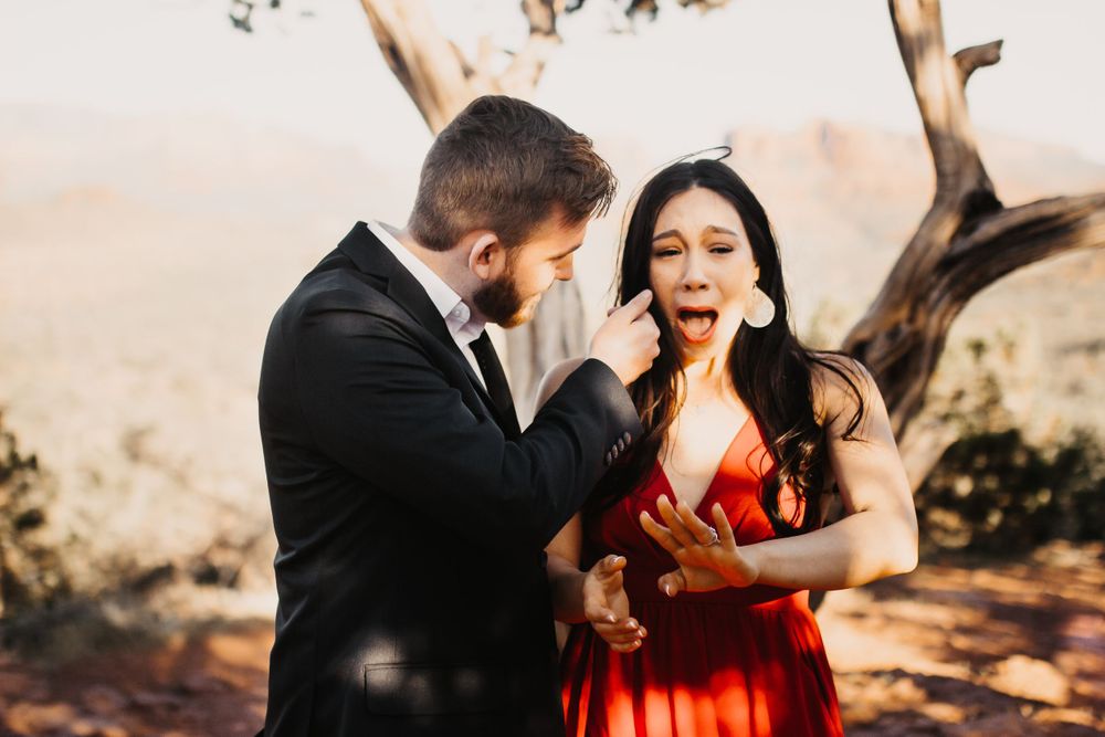 A couple celebrates their engagement in a scenic outdoor setting with warm lighting.