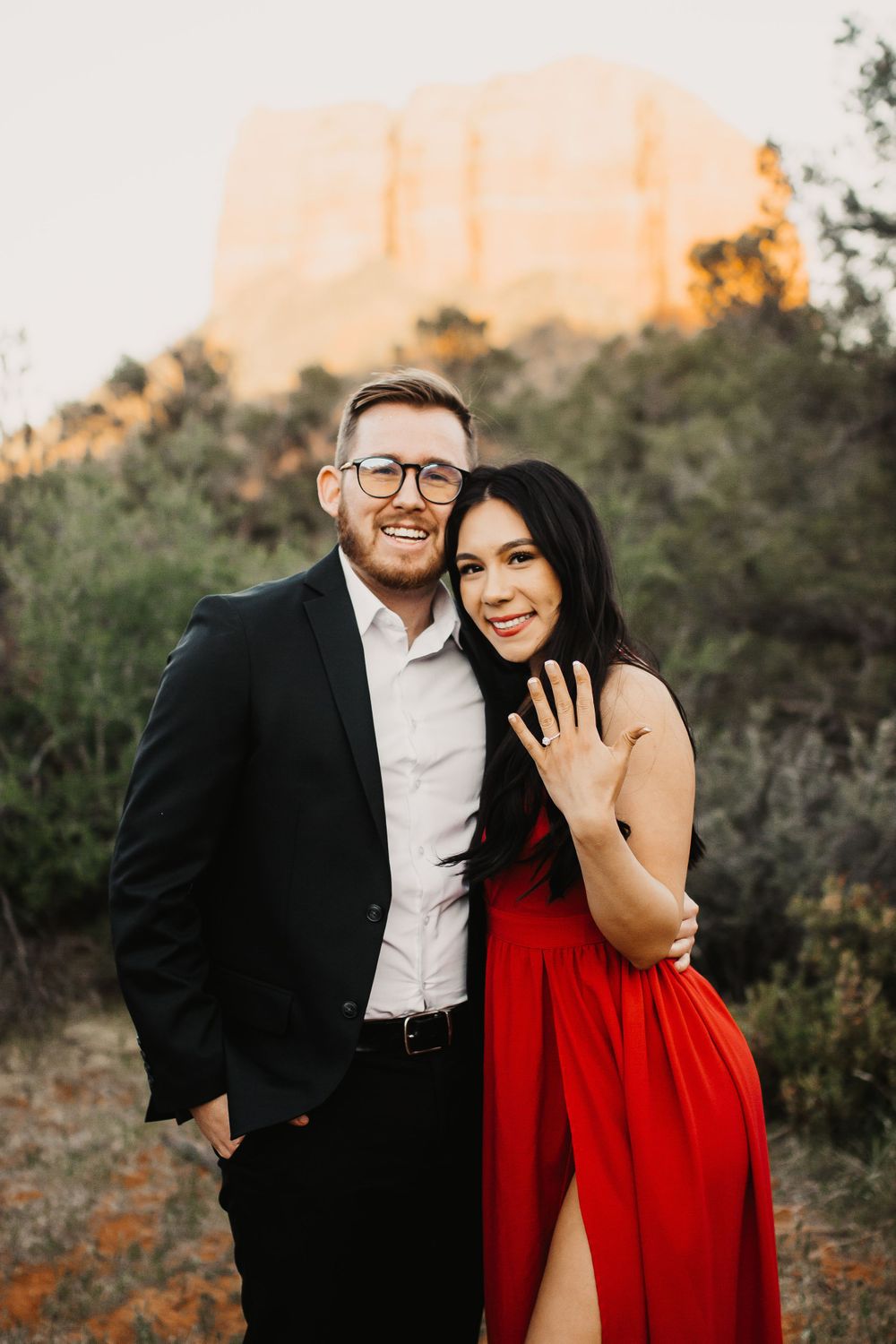 Joyful engagement photos at sunset with mountains in background and woman showing ring.
