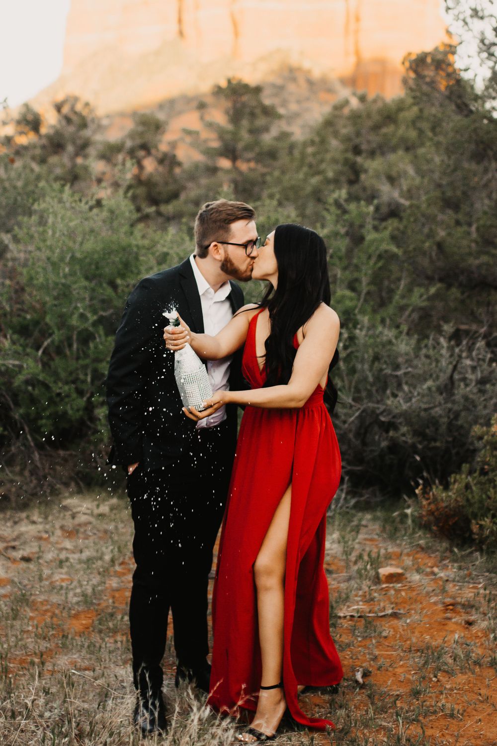 Playful engagement session in desert with couple in formal attire and confetti.