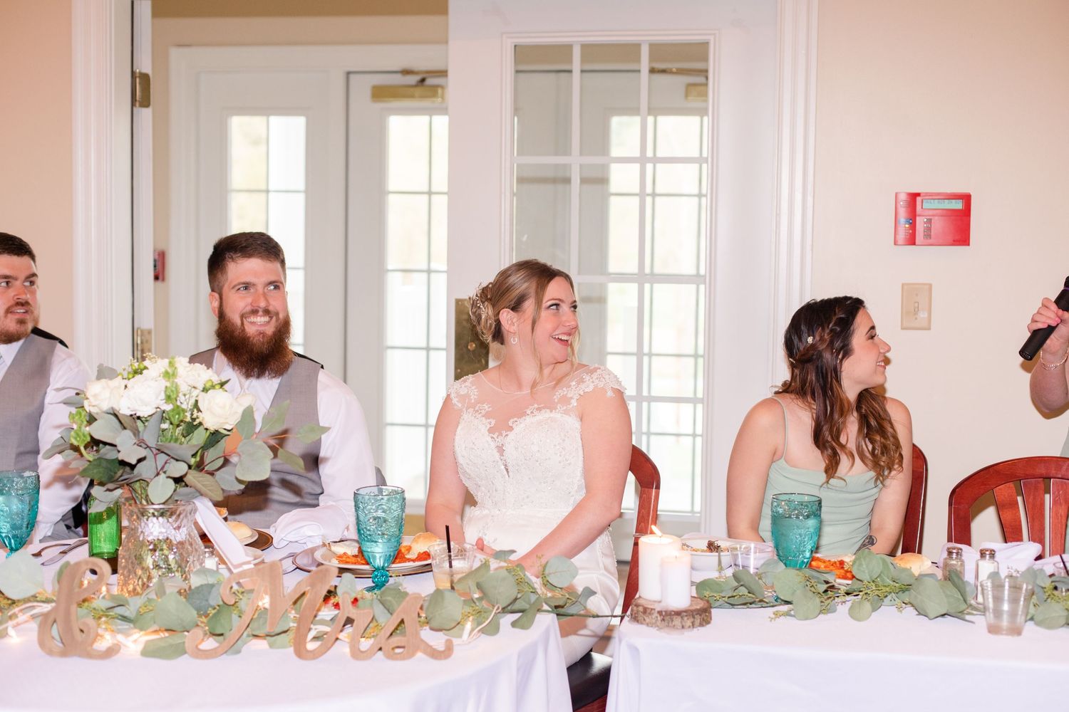 Wedding reception guests seated at elegant tables with turquoise decor and floral centerpieces.