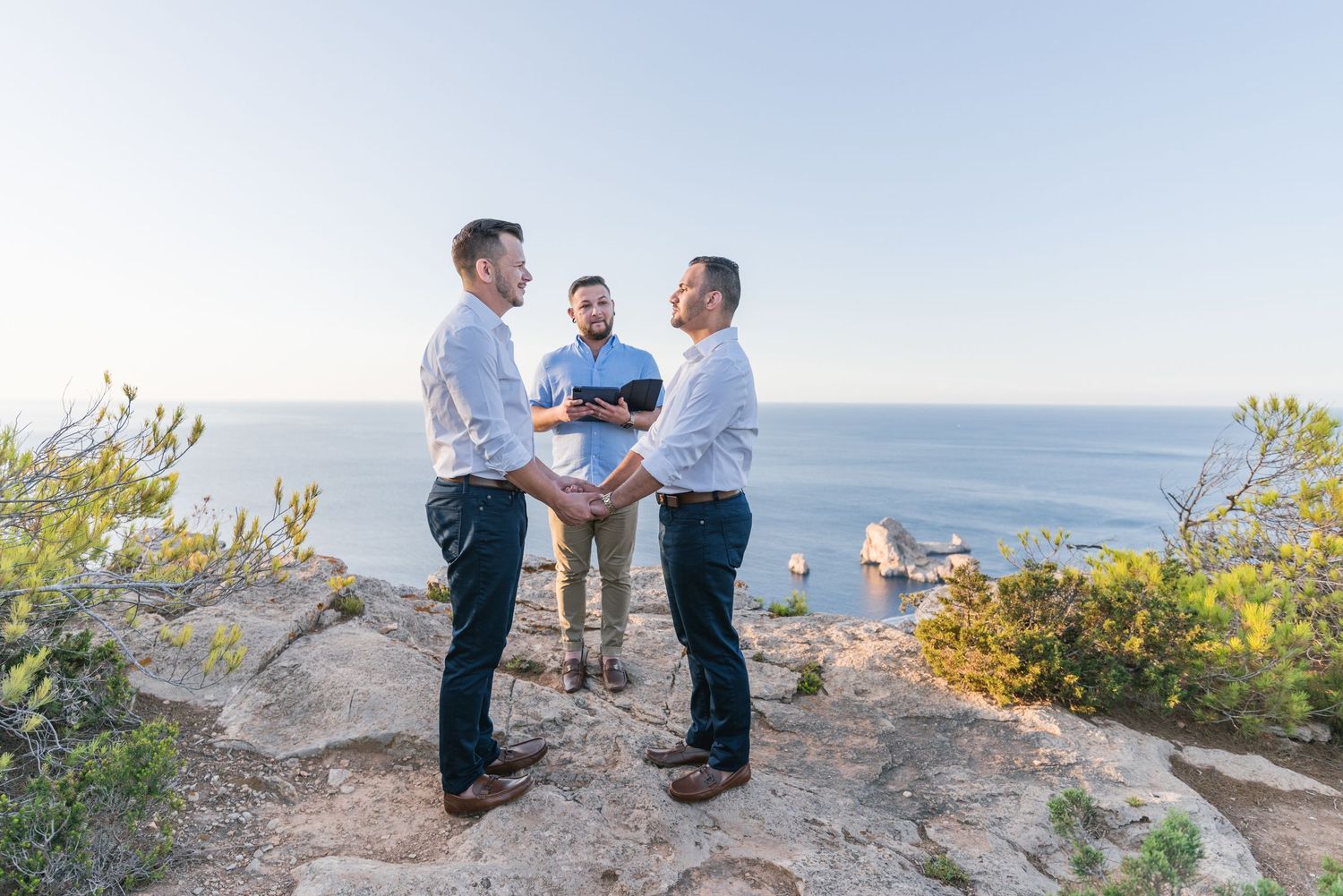 A gay couple take their vows in Ibiza at the top of a cliff with view of a blue sea