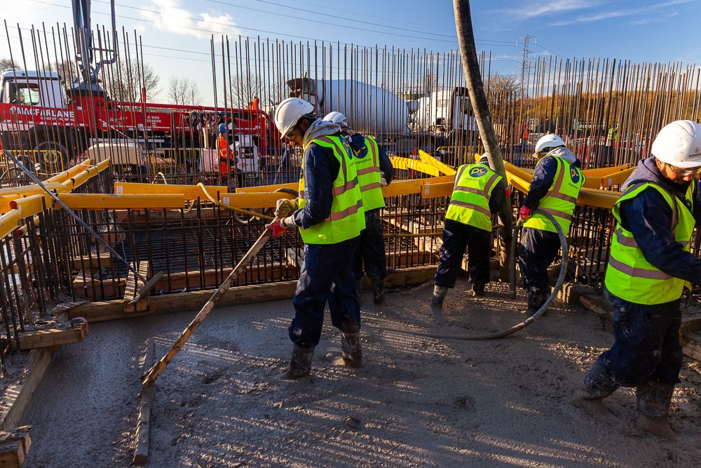 Construction photograph of workers concrete poring on rebar