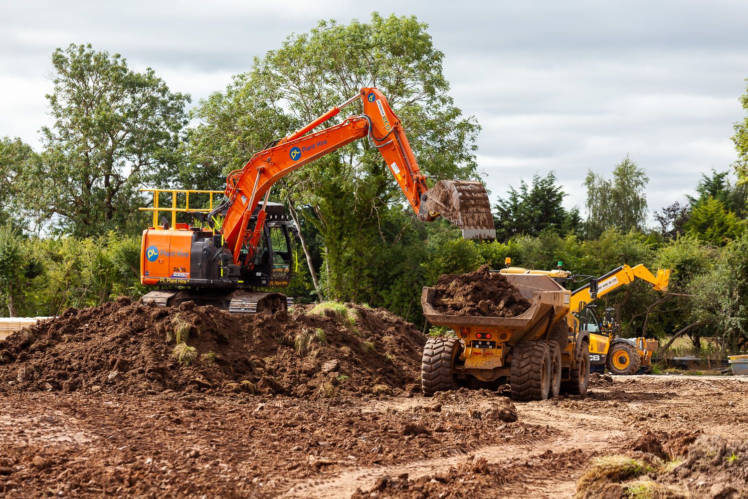 Construction photograph of digger loading dumper on housing site