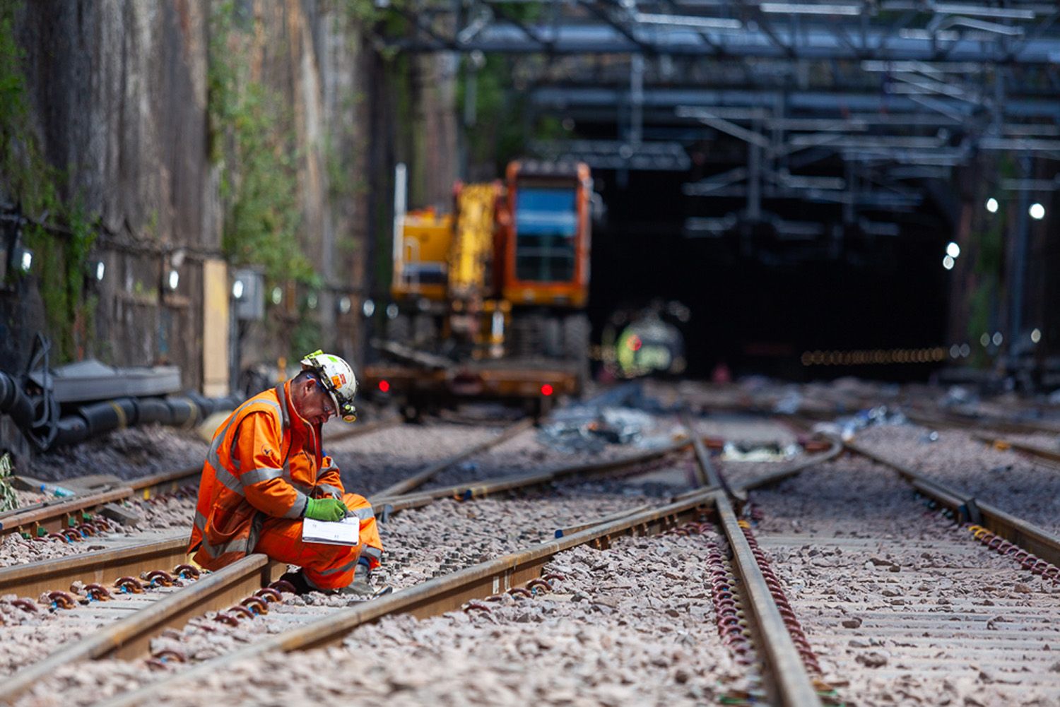 Worker looking at documents on Liverpool Lime Street Rail with Machinery in background