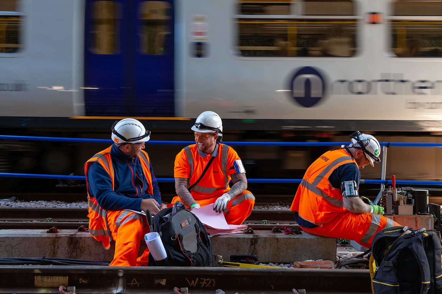 Construction Railway workers on track with train passing in background