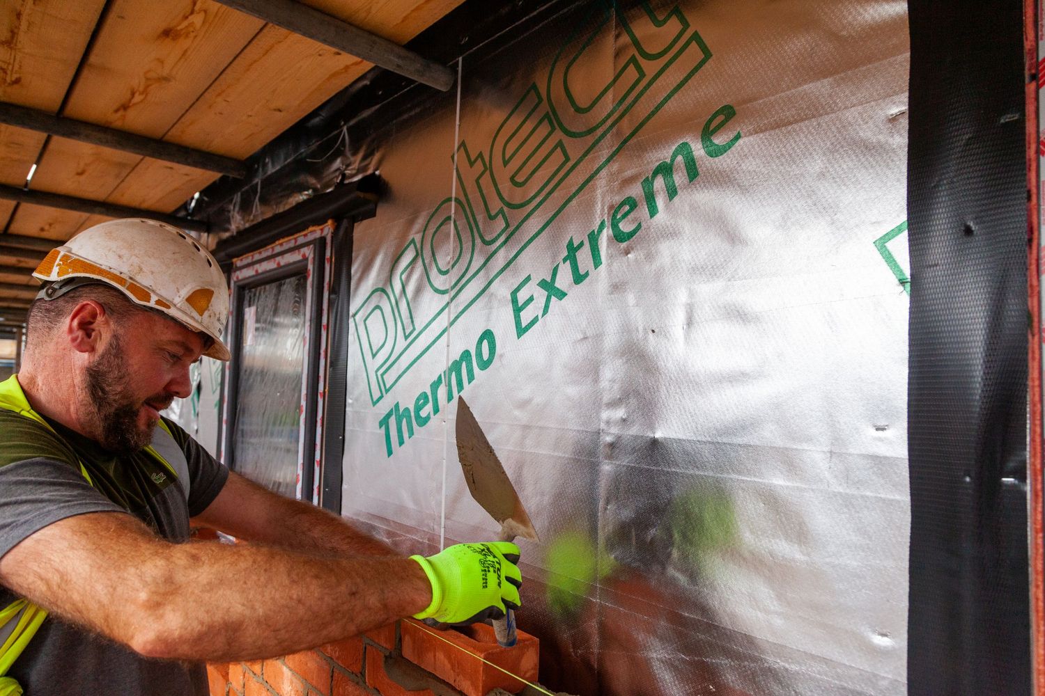 Construction photograph of bricklaying over insulation panels