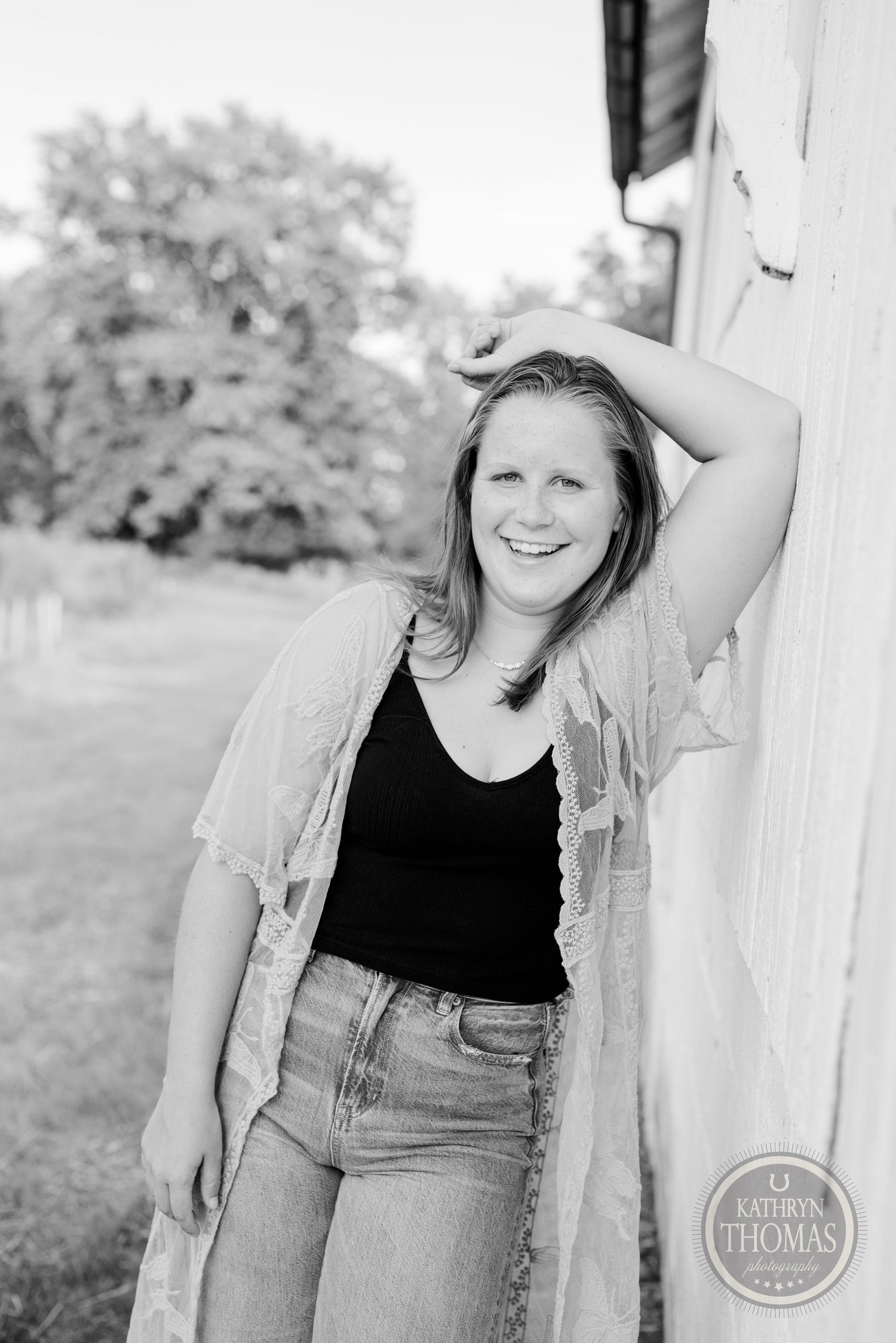 Black and white portrait of someone posing against a white wall in casual summer attire.
