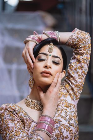 Artistic portrait showcasing intricate bridal makeup, jewelry and embroidered outfit details.
