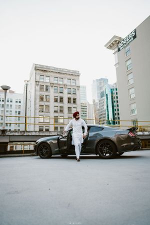 A sleek black sports car parked in an urban setting with city buildings in the background.