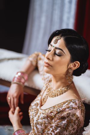 Close-up portrait showcasing intricate bridal jewelry and embroidered pink and gold attire.