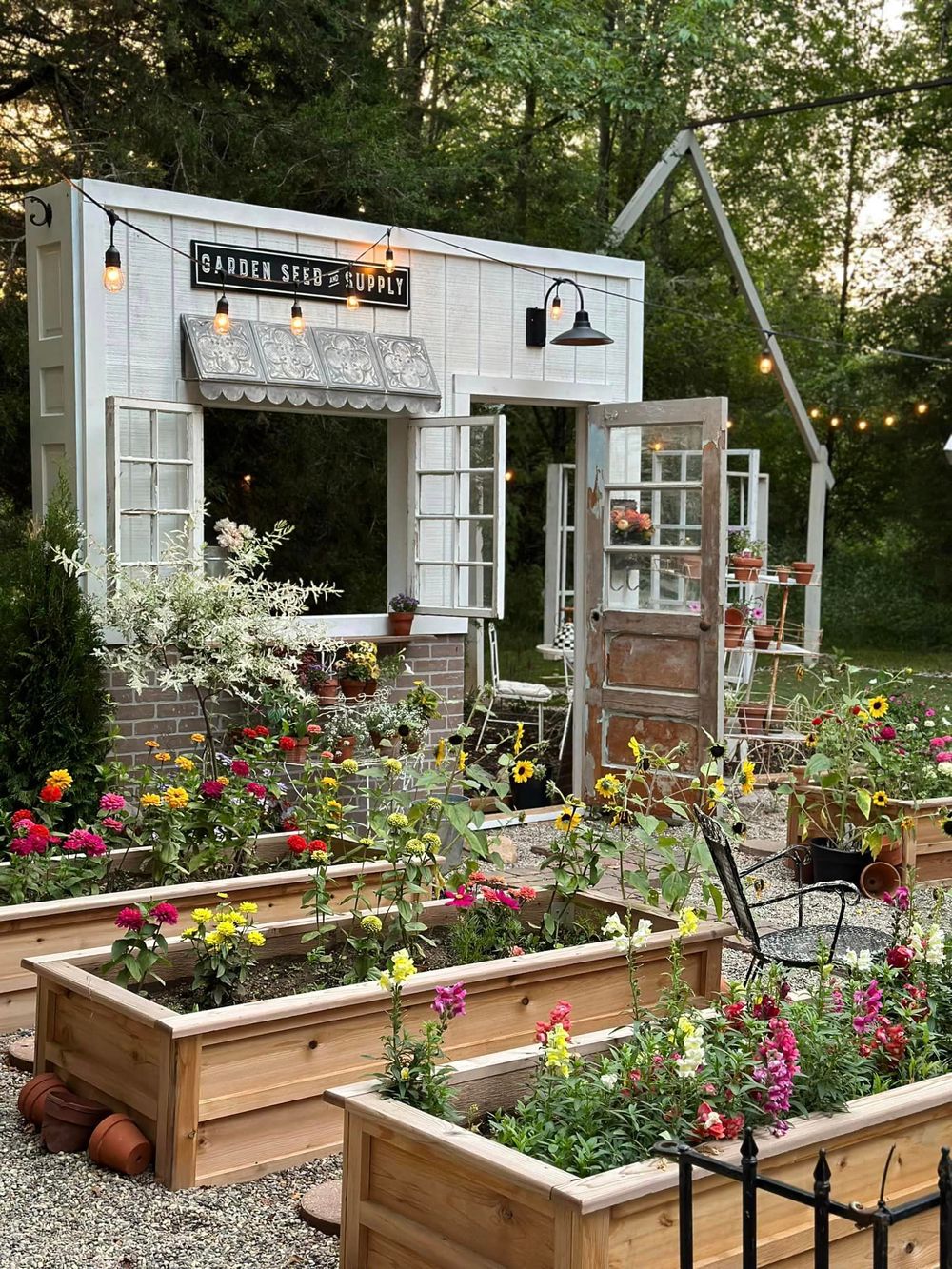 Charming garden shed with raised flower beds and string lights creating a cozy outdoor space.
