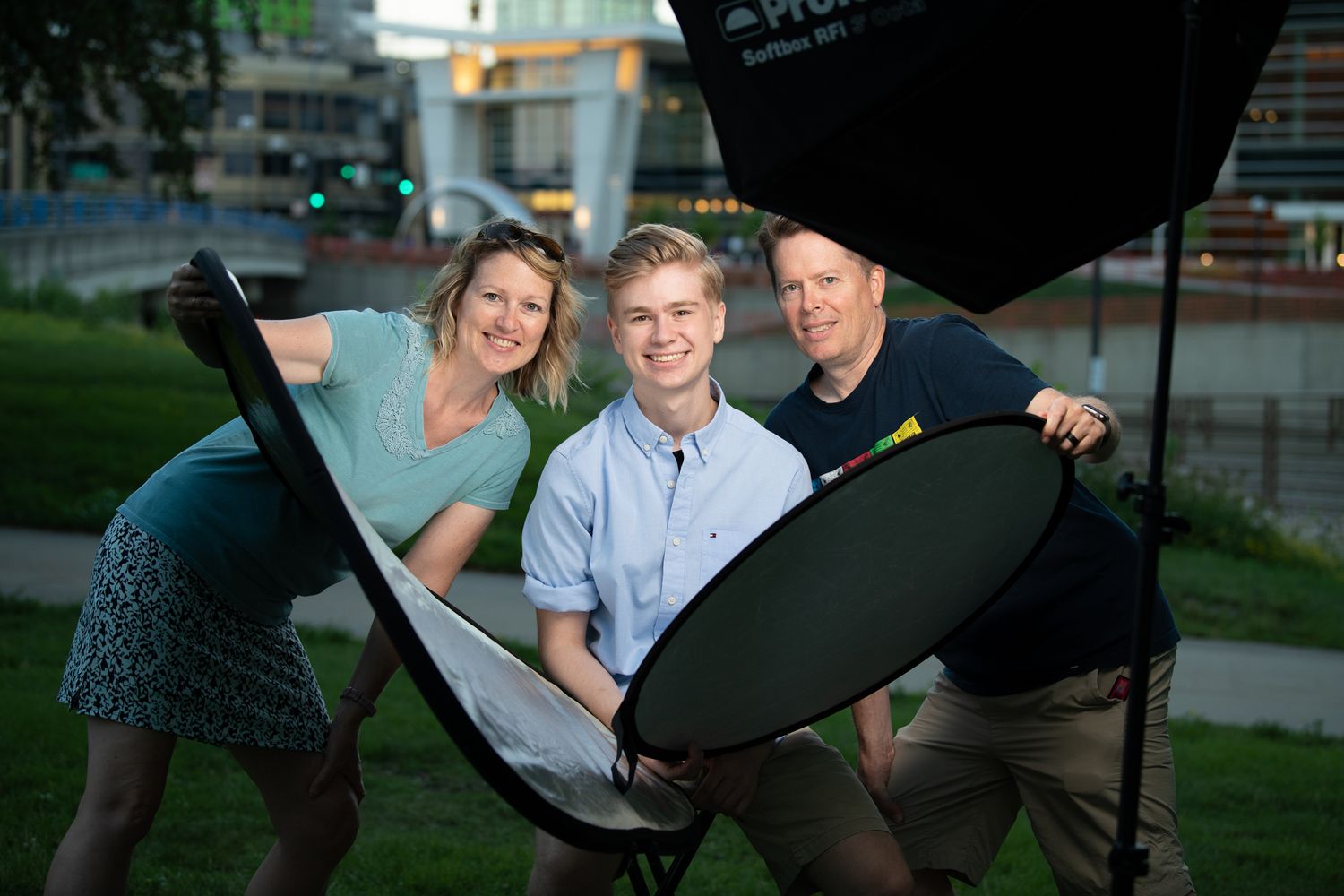 Behind the scenes photo of people holding reflectors during outdoor photography session.