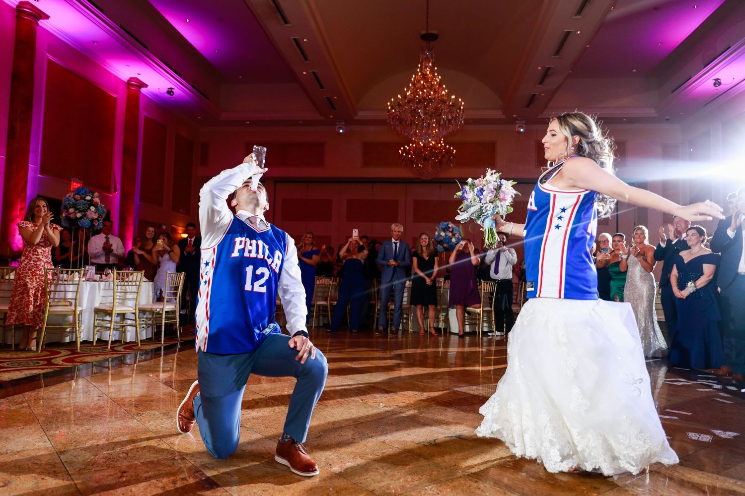 Bride and groom in Philadelphia 76ers jerseys performing a fun surprise dance at their reception.