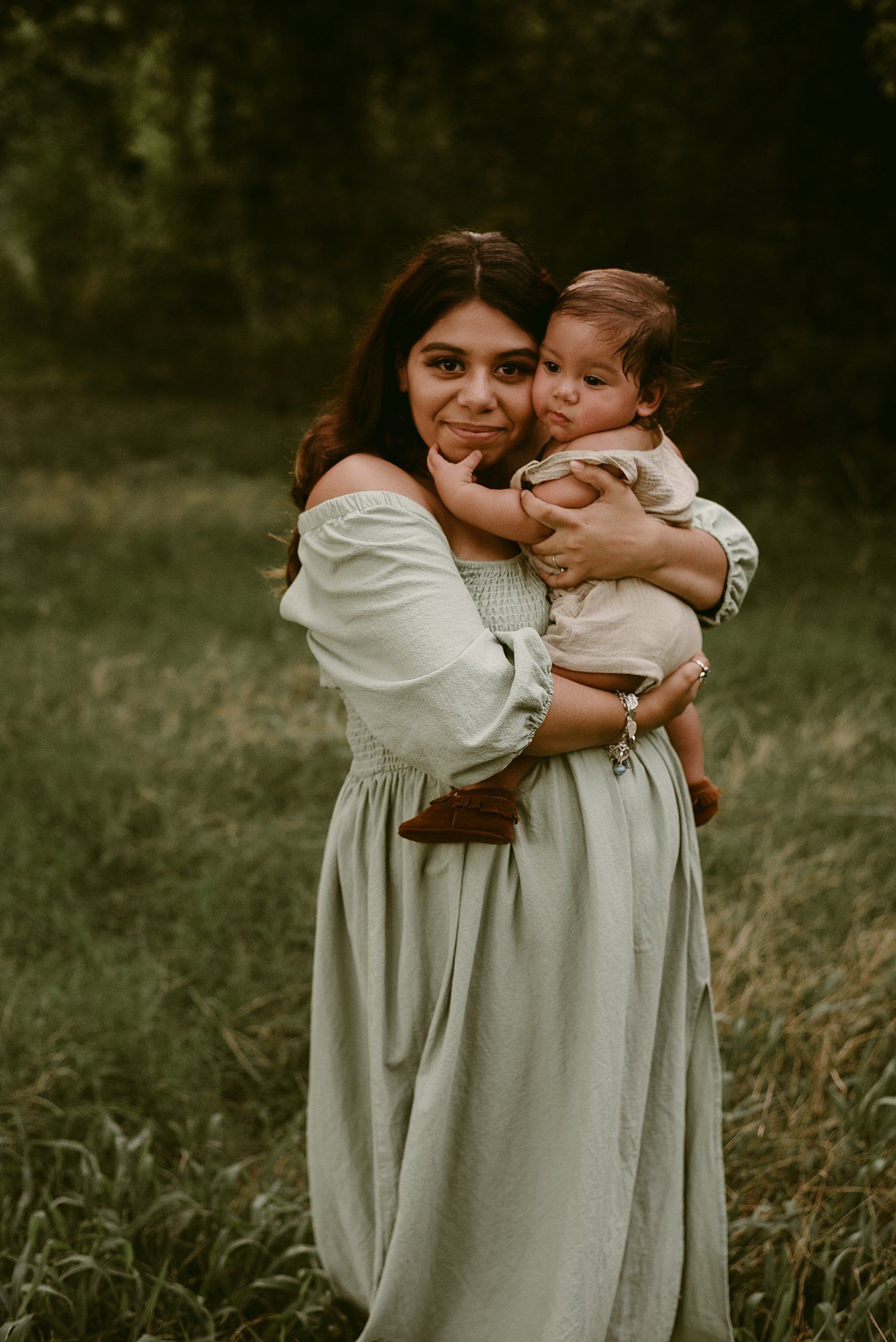 A tender moment between parent and child outdoors, both wearing light-colored clothing.