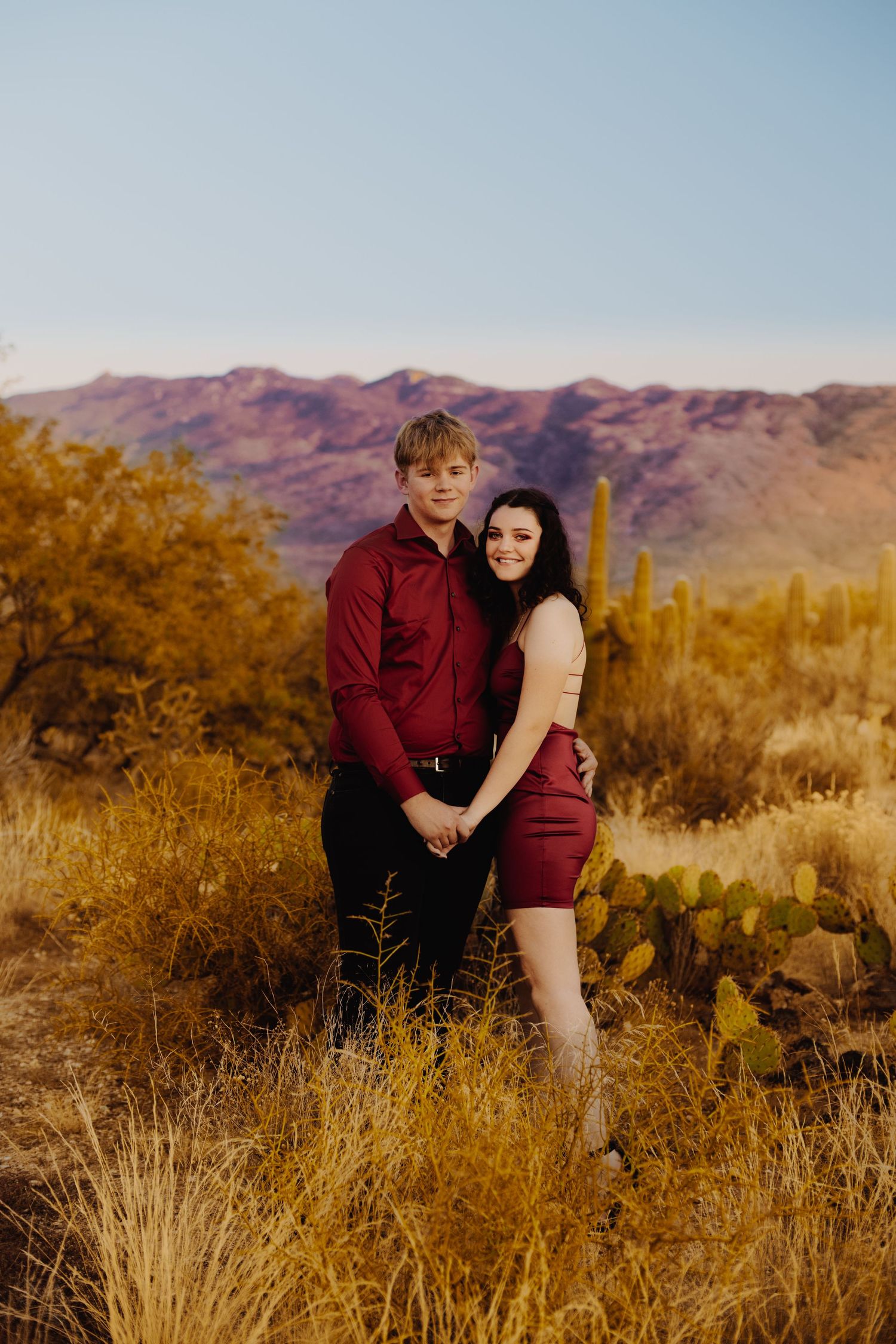 Desert landscape photography session at golden hour with mountains and saguaro cacti in the background.