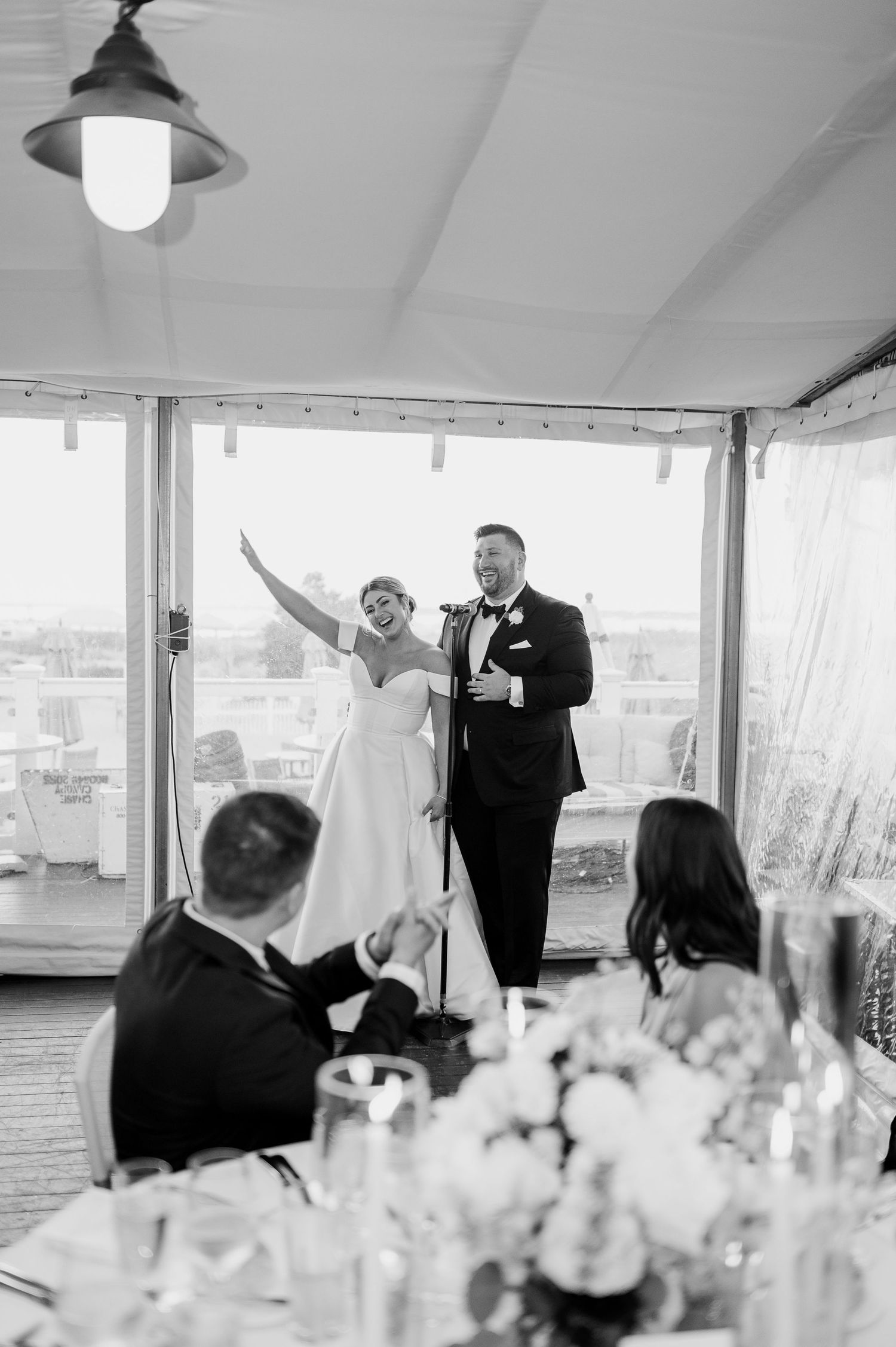 Wedding guests raise their glasses in celebration during a toast at an elegant indoor reception.