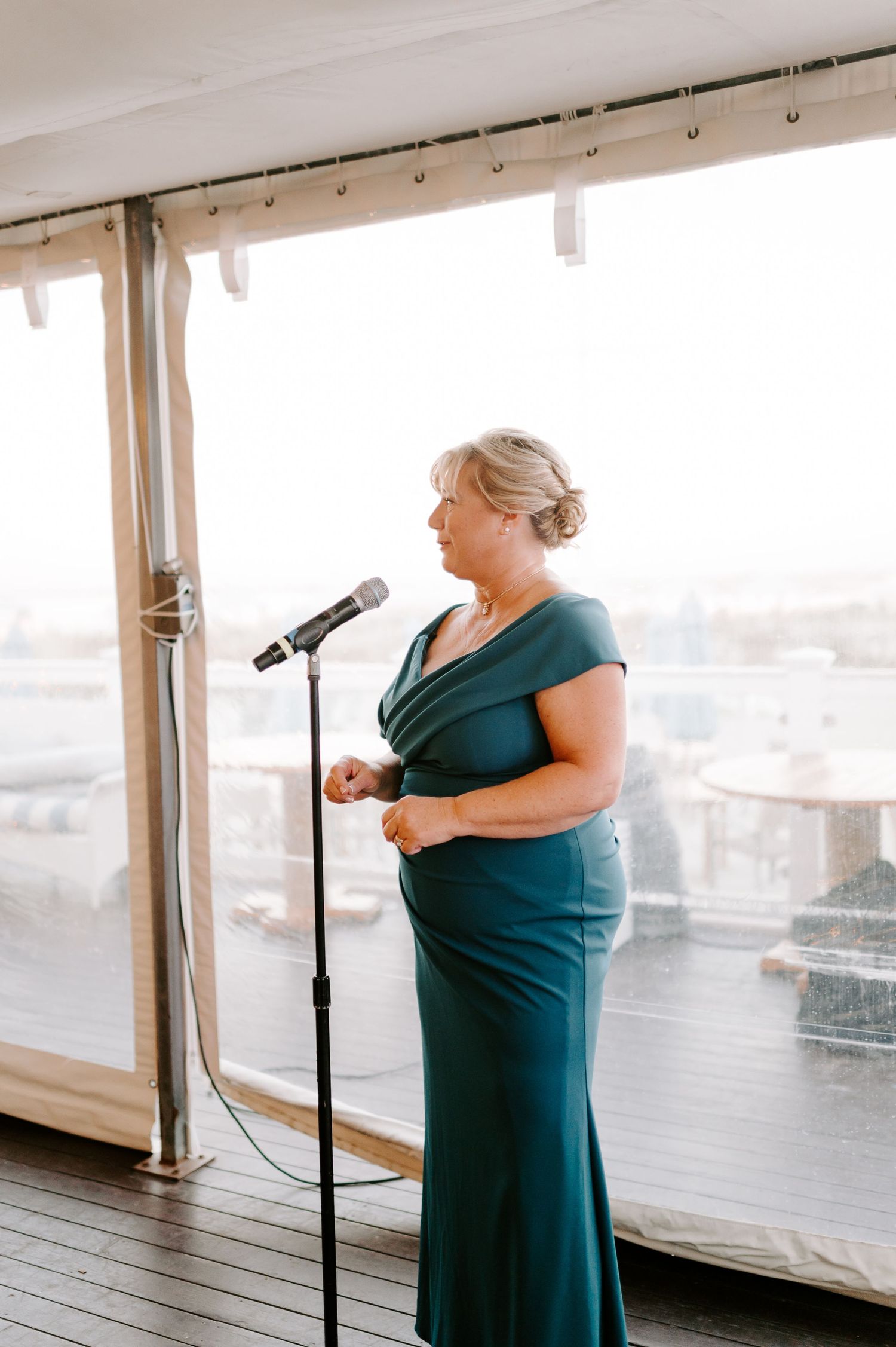 Woman in a navy blue dress gives an emotional speech at a wedding reception.
