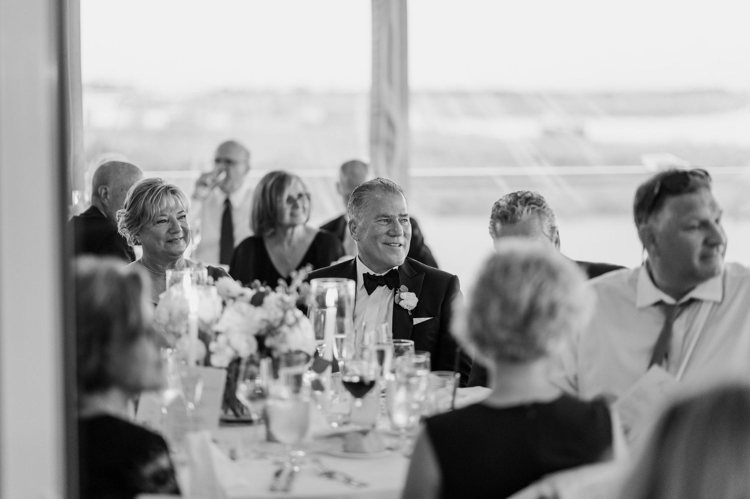 Wedding reception guests seated at tables in an elegant white dining room.