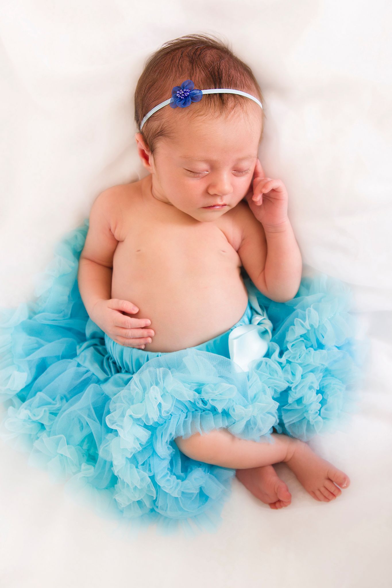 baby sleeping on her back wearing a blue tutu