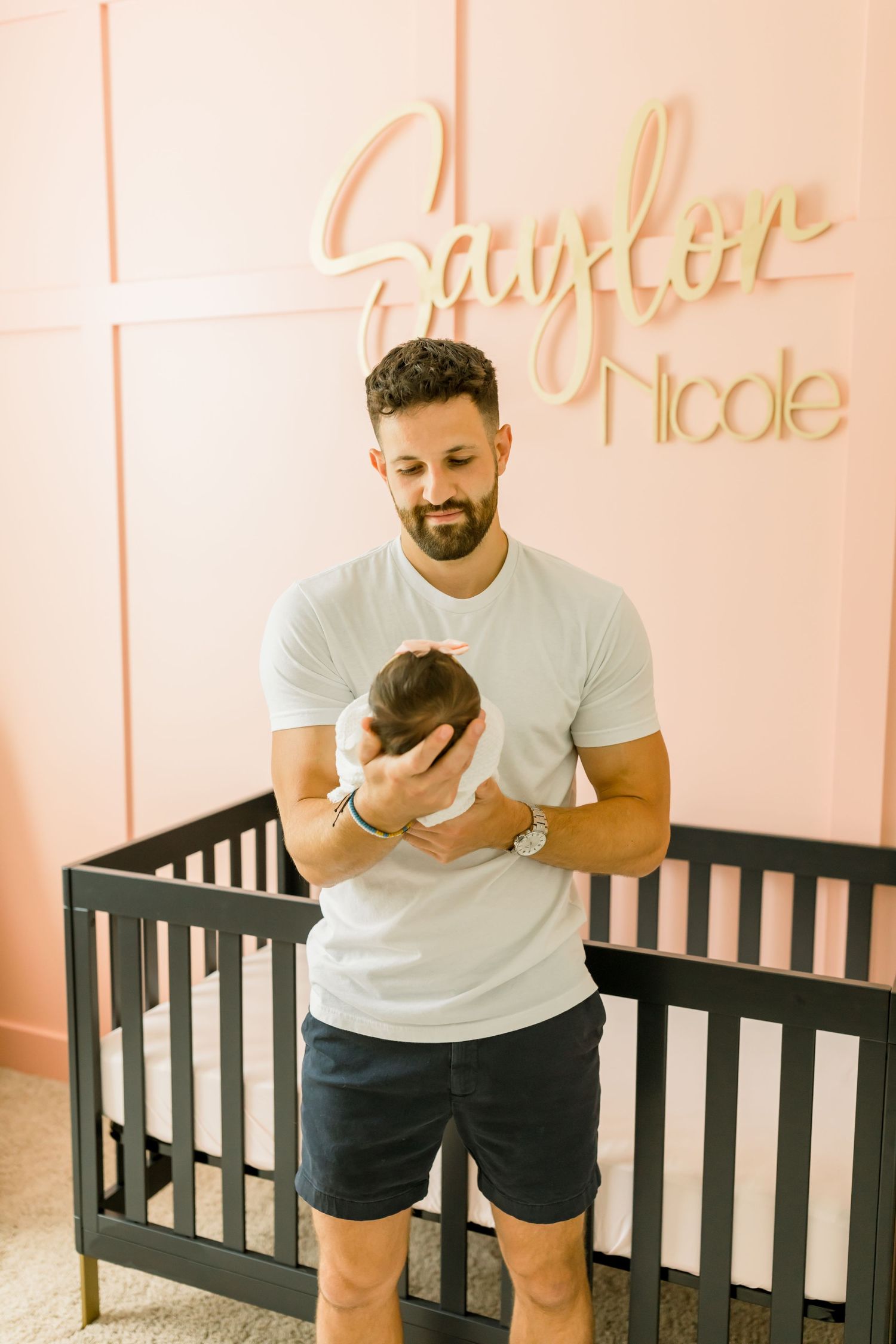 Modern nursery with coral walls featuring gold 'Saylor Nicole' wall decor.