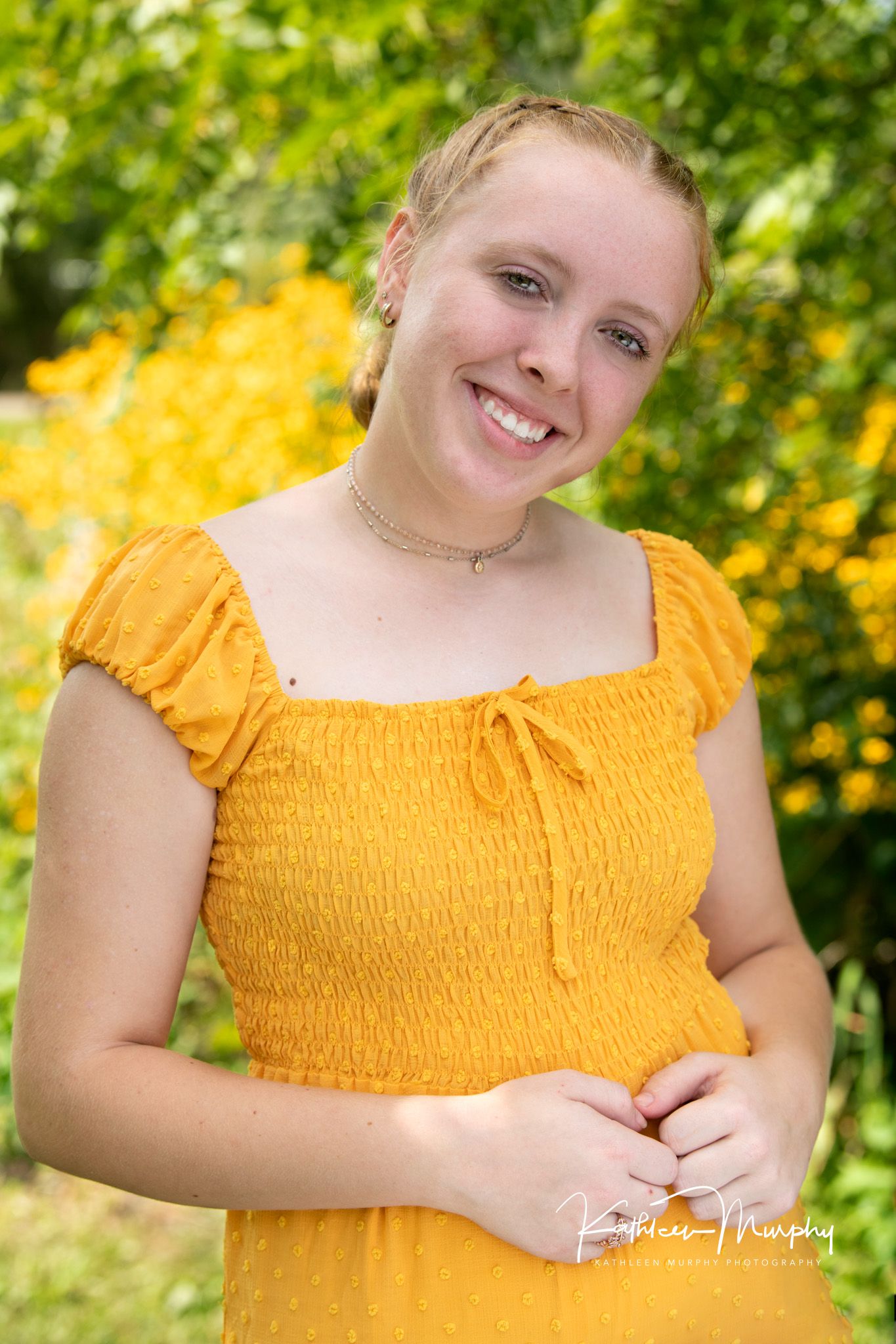 A bright yellow smocked dress complements a summer garden setting with yellow flowers in the background.