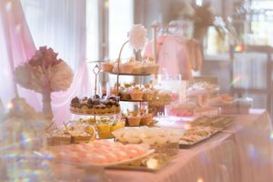 Soft focus image of an elegant dessert table with tiered serving platters and pink decorative elements.
