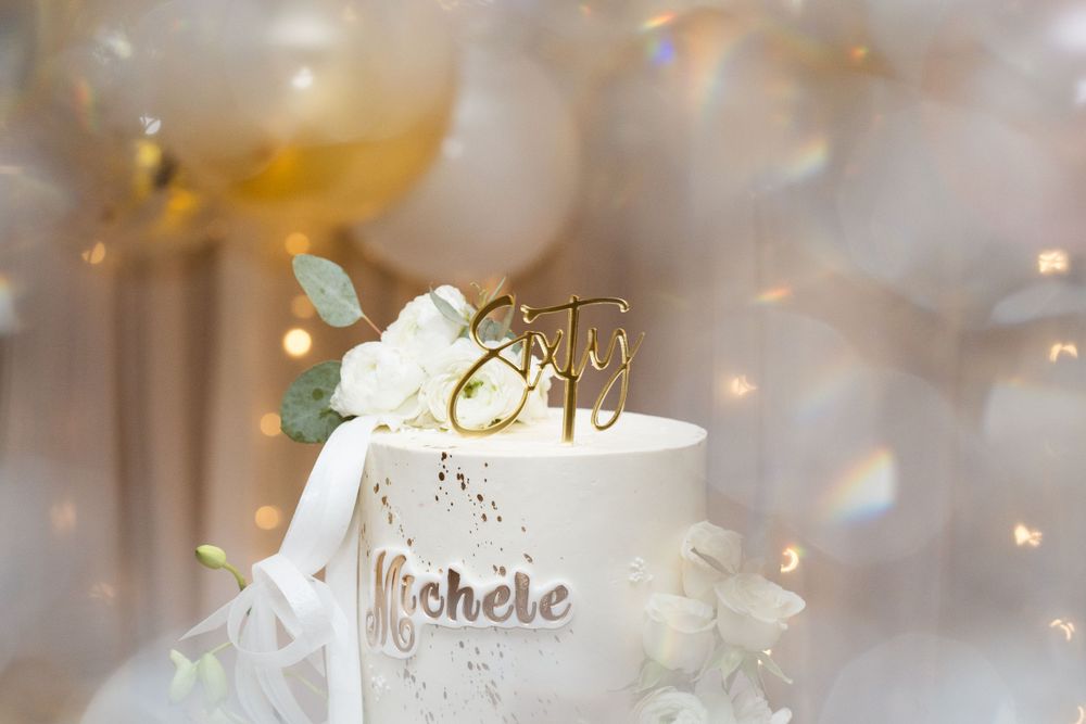 A white wedding cake topper detail shot with soft bokeh lights in the background.