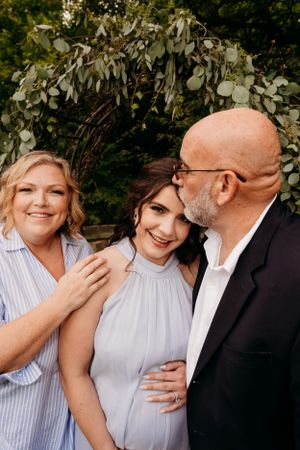 A joyful family moment captured under a rustic greenery arch outdoors.