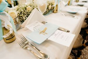 Baby shower menu and place settings with baby's breath flowers and elegant silverware on white tablecloth in the Hudson Valley,NY.