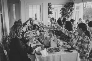 A group toasts and celebrates around an elegant dining table set with plates and glasses.