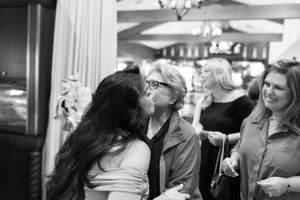 Black and white candid photograph of guests interacting at an indoor event.