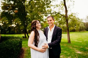A tender maternity photo captured outdoors in a lush garden setting.