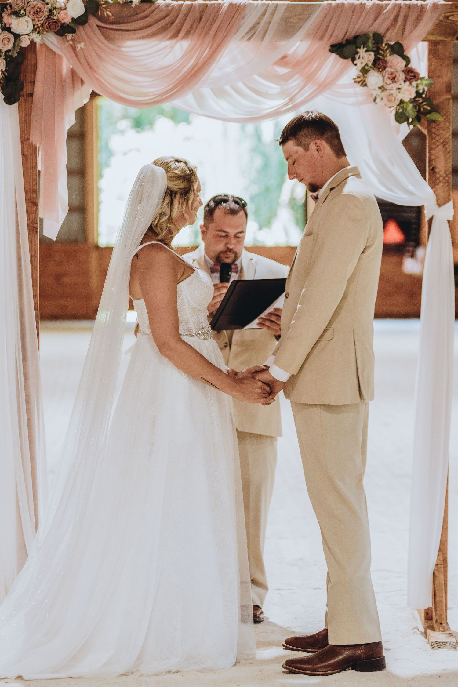 Wedding ceremony setup with elegant white draping and floral arrangements in a rustic venue.