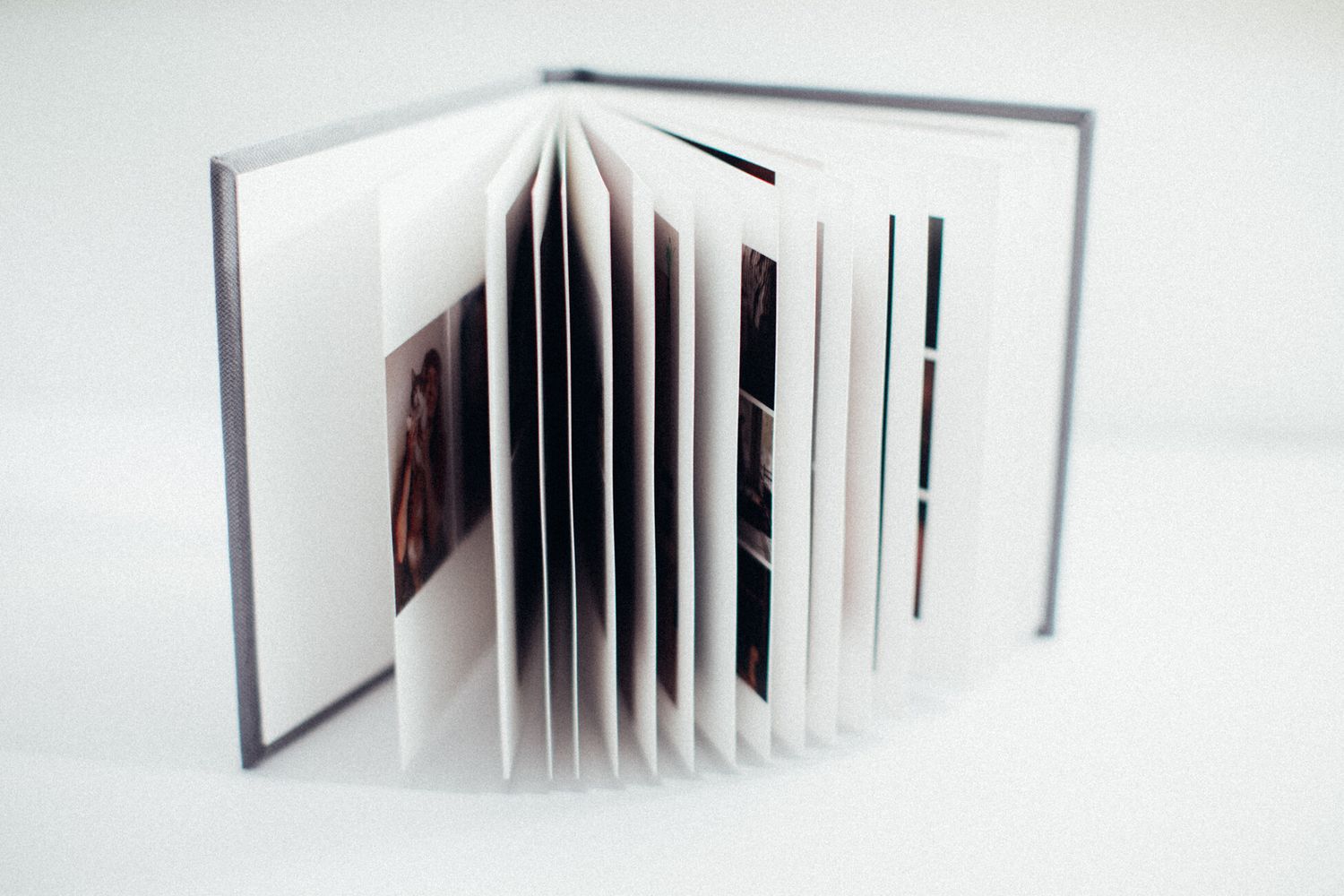 An open white photo album displaying multiple pages with photographs inside.