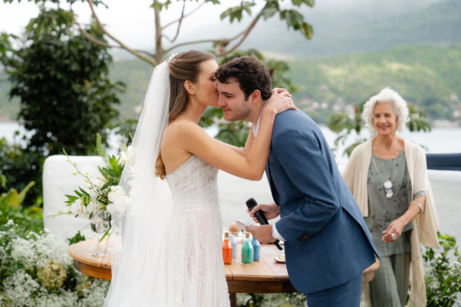 Couple shares intimate moment during outdoor wedding ceremony with mountain backdrop.