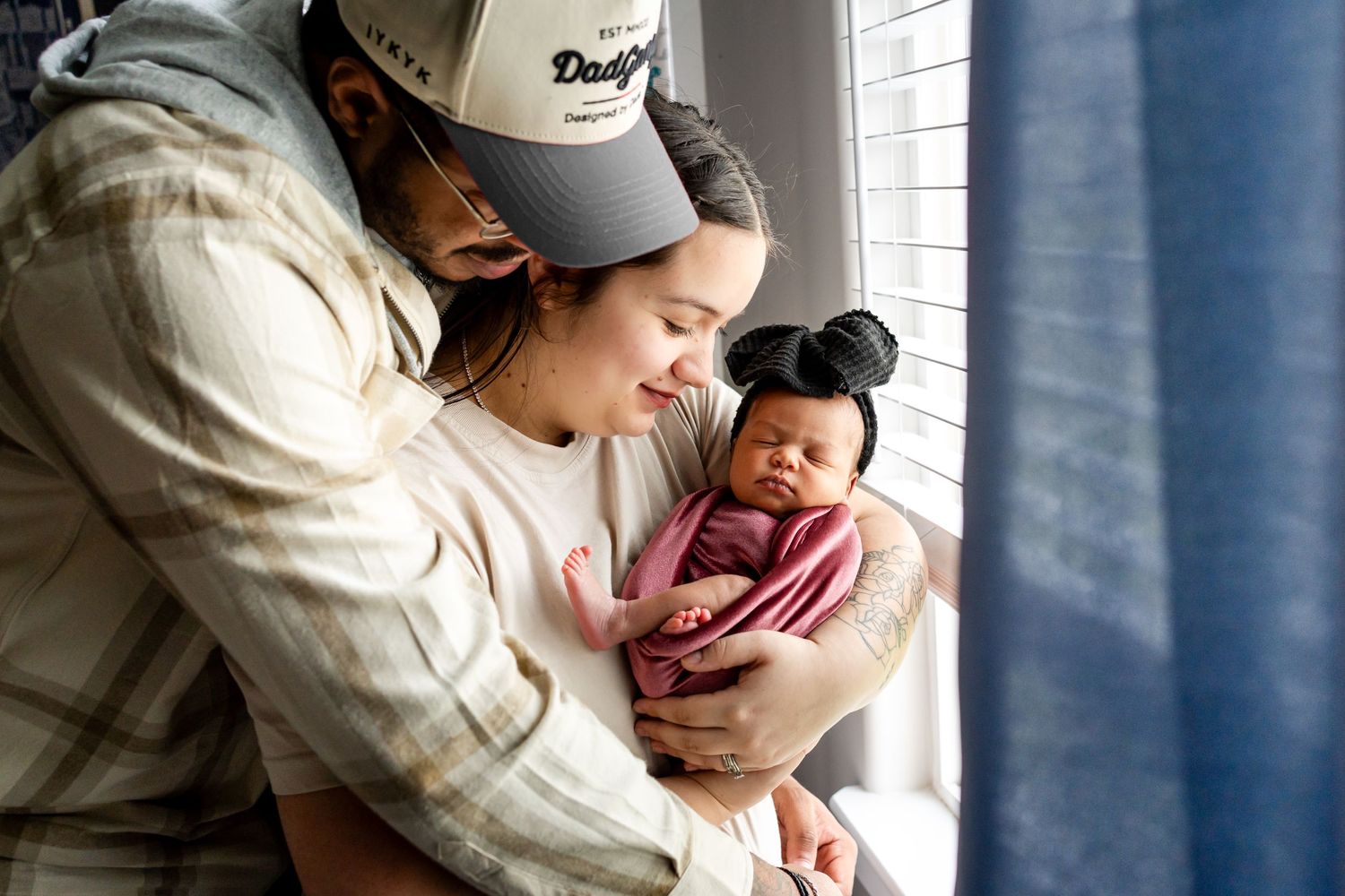 mom and dad with baby girl by the window