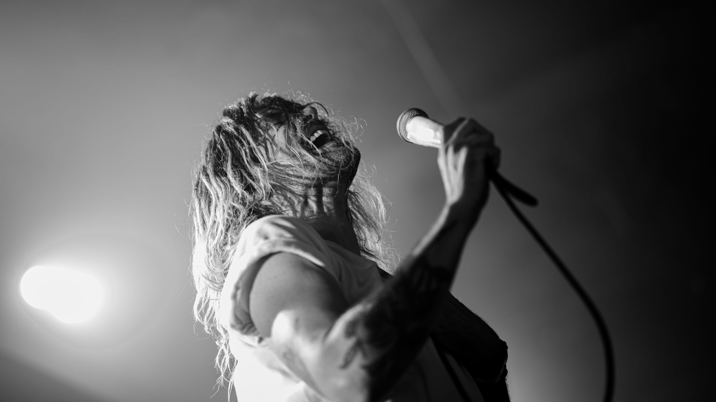 Dramatic black and white concert photo showing a performer singing passionately on stage.