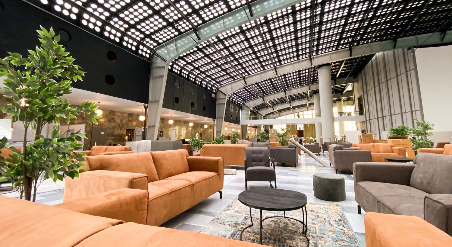 Conference hall furnished with gray and congnack colored sofas and poufs, rugs and coffee tables