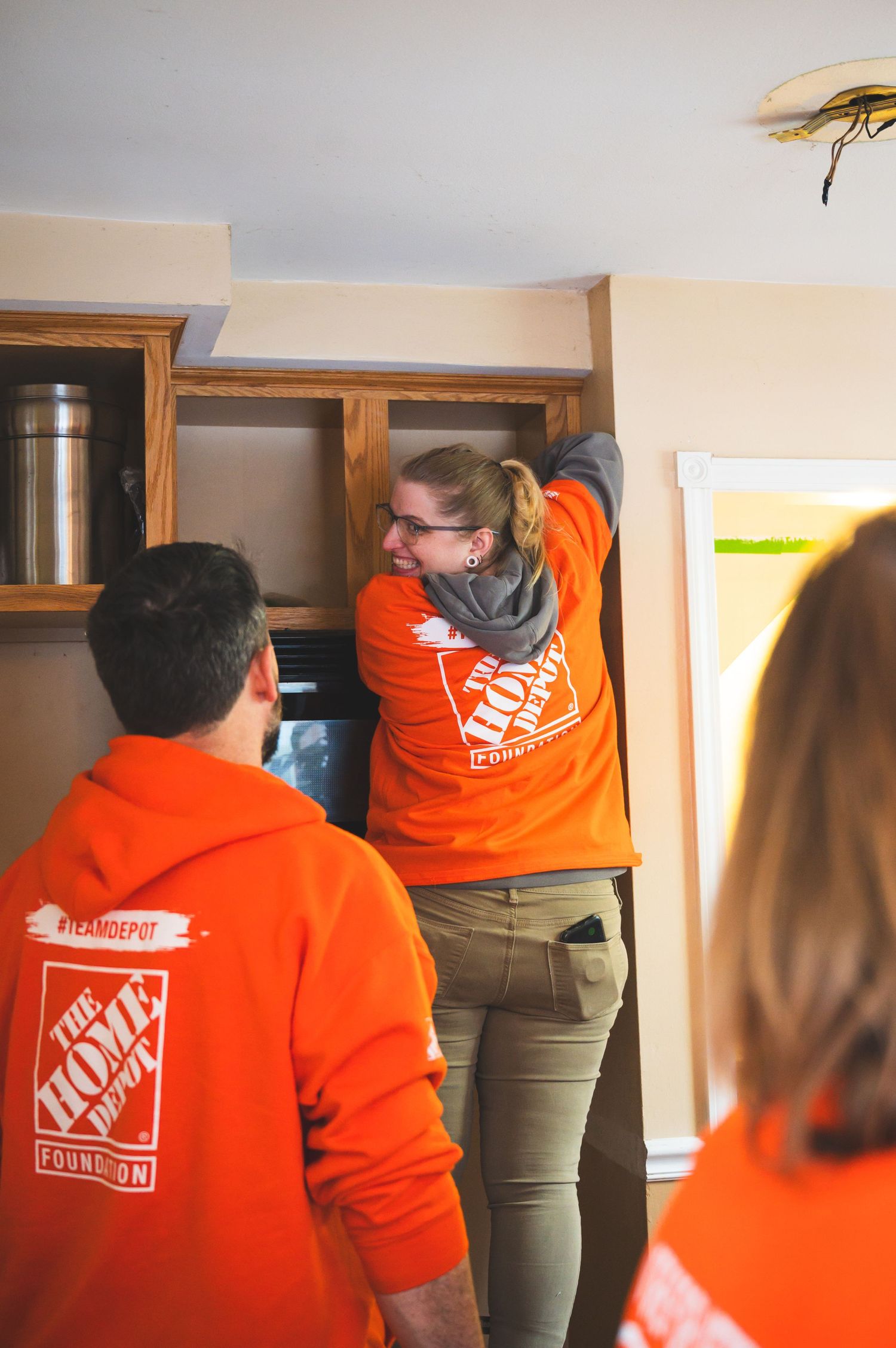 Home Depot volunteers in orange hoodies work on a home improvement project together.