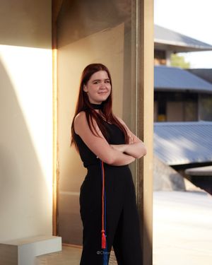 Environmental portrait against a building with warm lighting and architectural details.