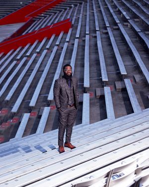Fashion portrait on geometric metal bleachers with red accent lighting and modern architectural elements.