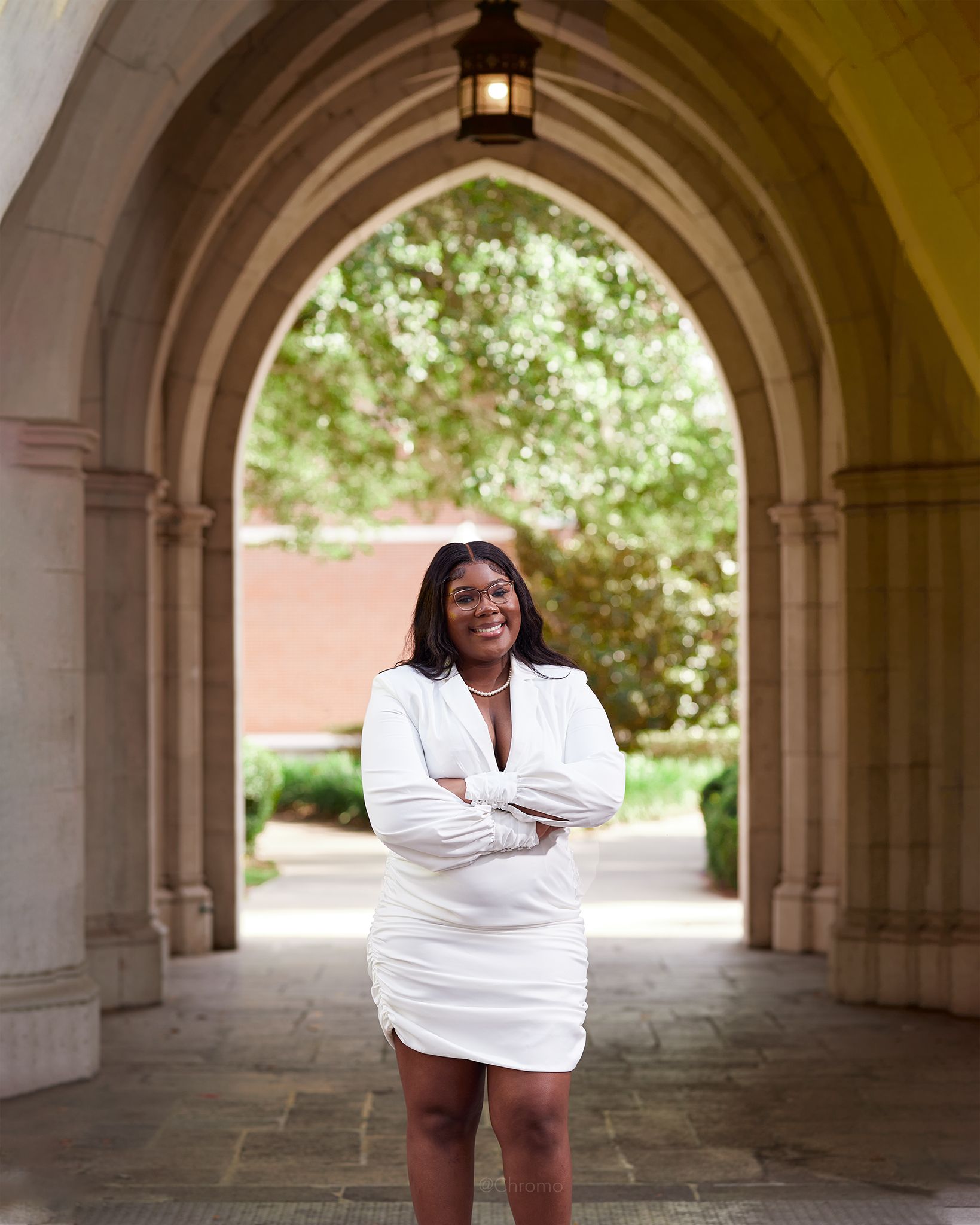 Confident pose under stone archway wearing crisp white professional attire.