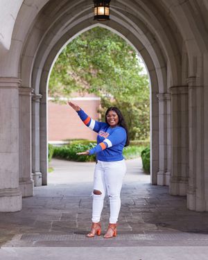 Joyful pose under gothic stone archway wearing bright blue and white casual outfit.