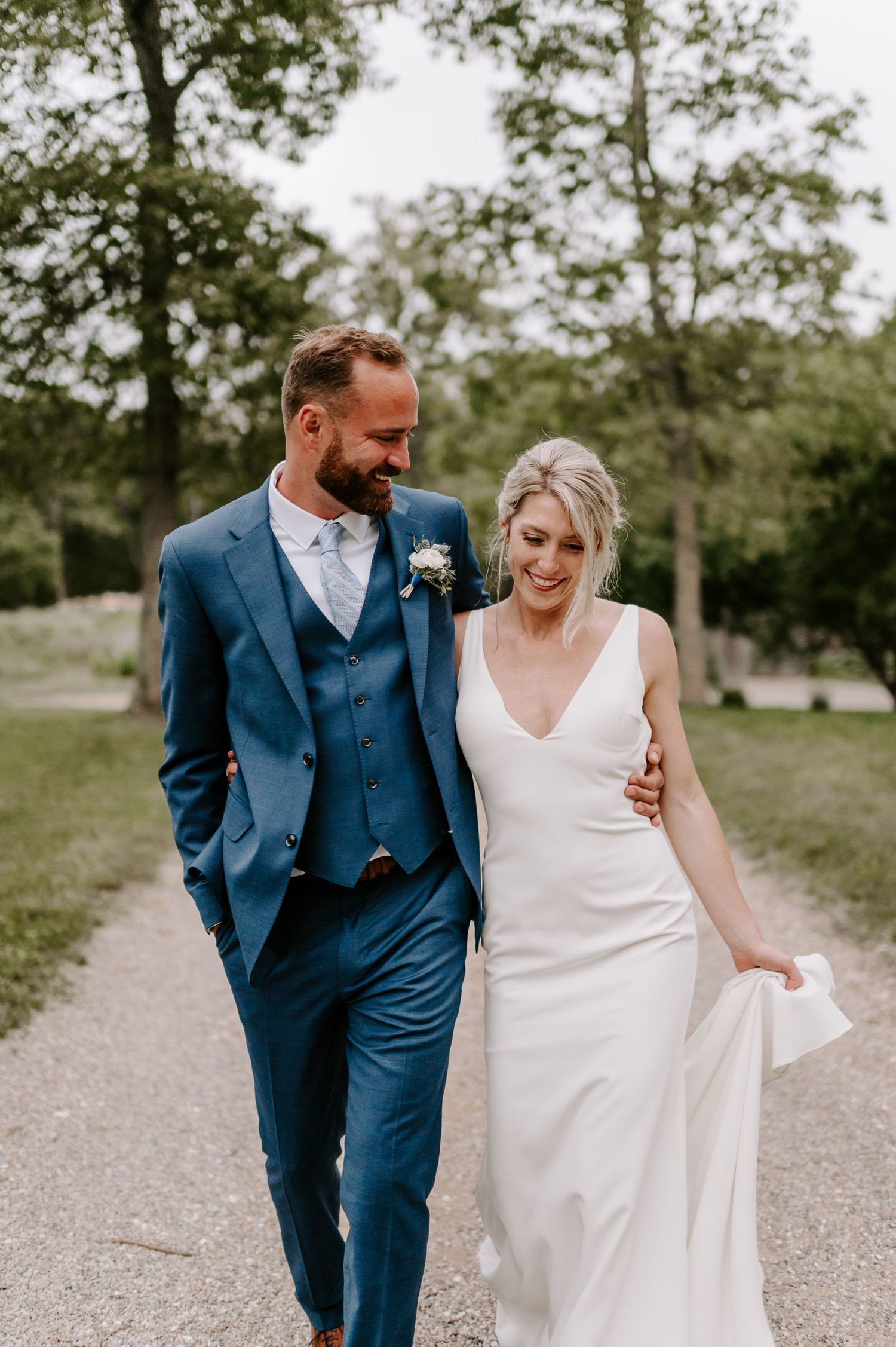 A couple laughs together while walking down a scenic outdoor path.