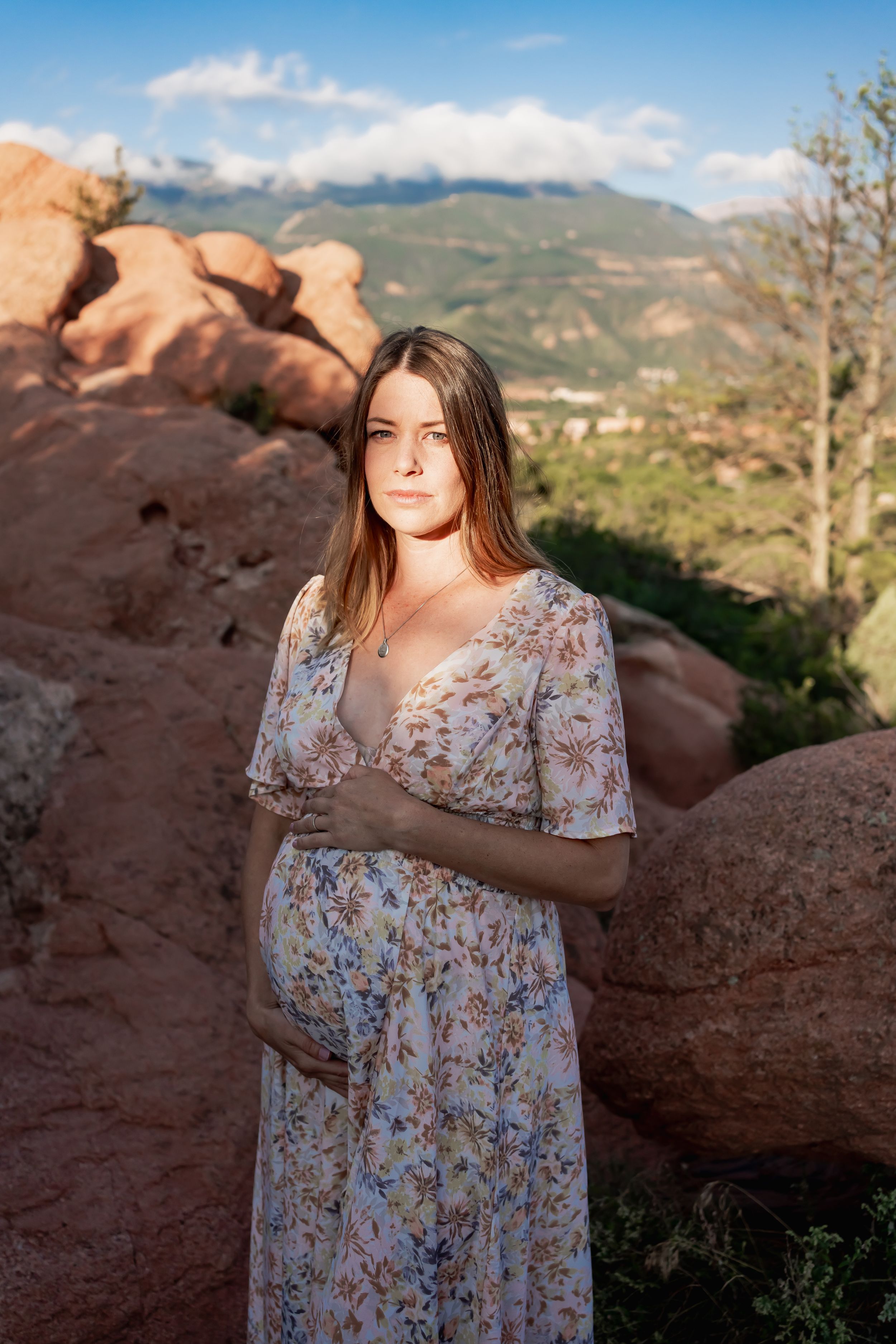 A floral maternity dress complements the natural beauty of rocky mountain landscapes during golden hour.