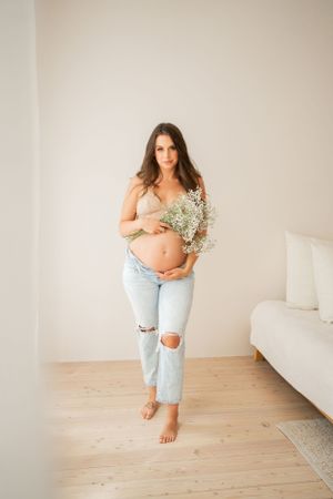 Casual maternity portrait with ripped jeans, baby's breath flowers and natural window lighting.