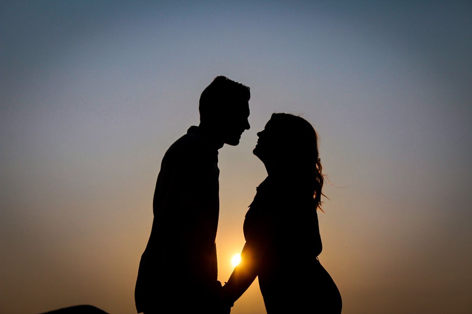 Silhouette of a couple holding hands at sunset looking at each other in the desert of Utah.