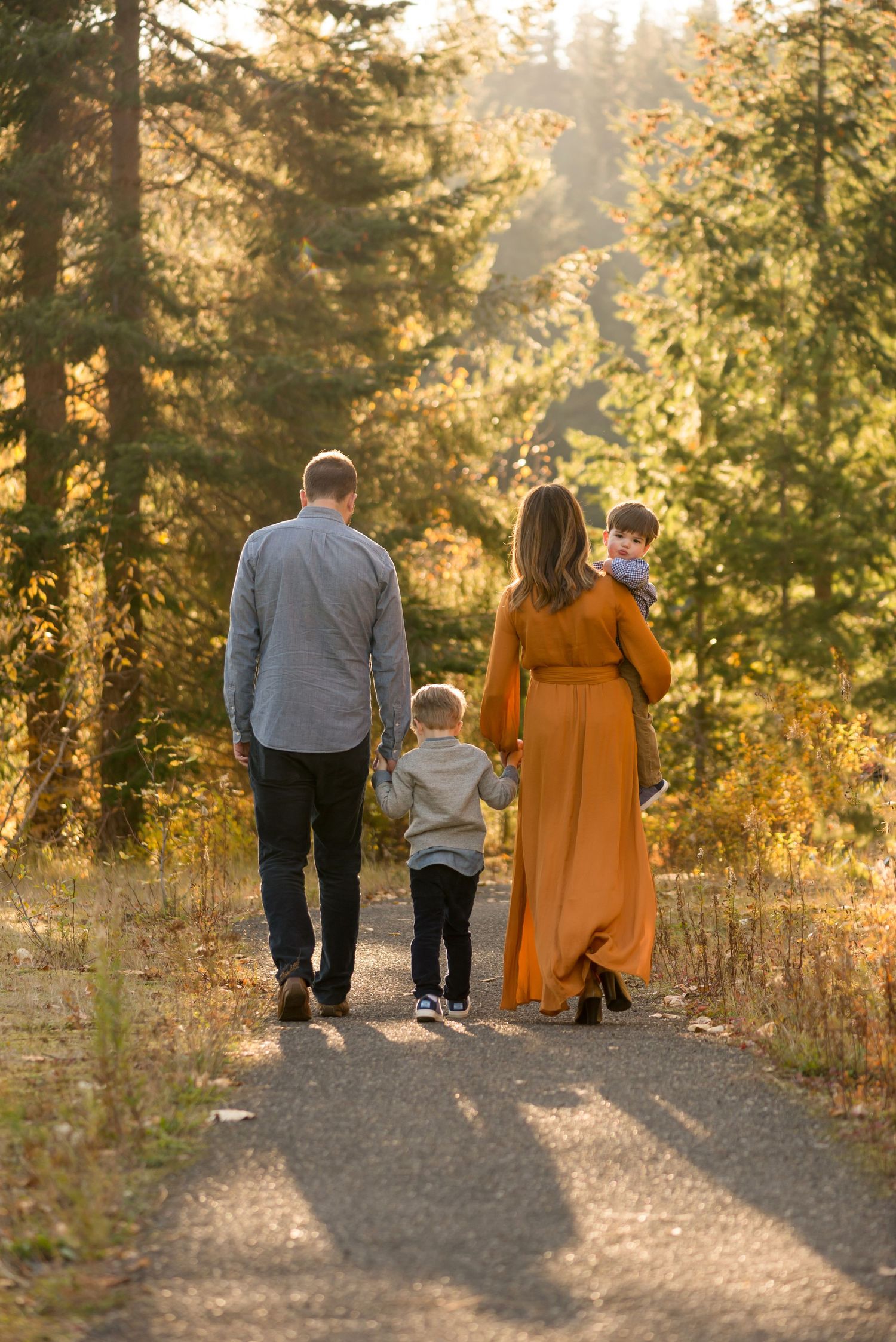 Family walking together on forest path during golden hour sunset.