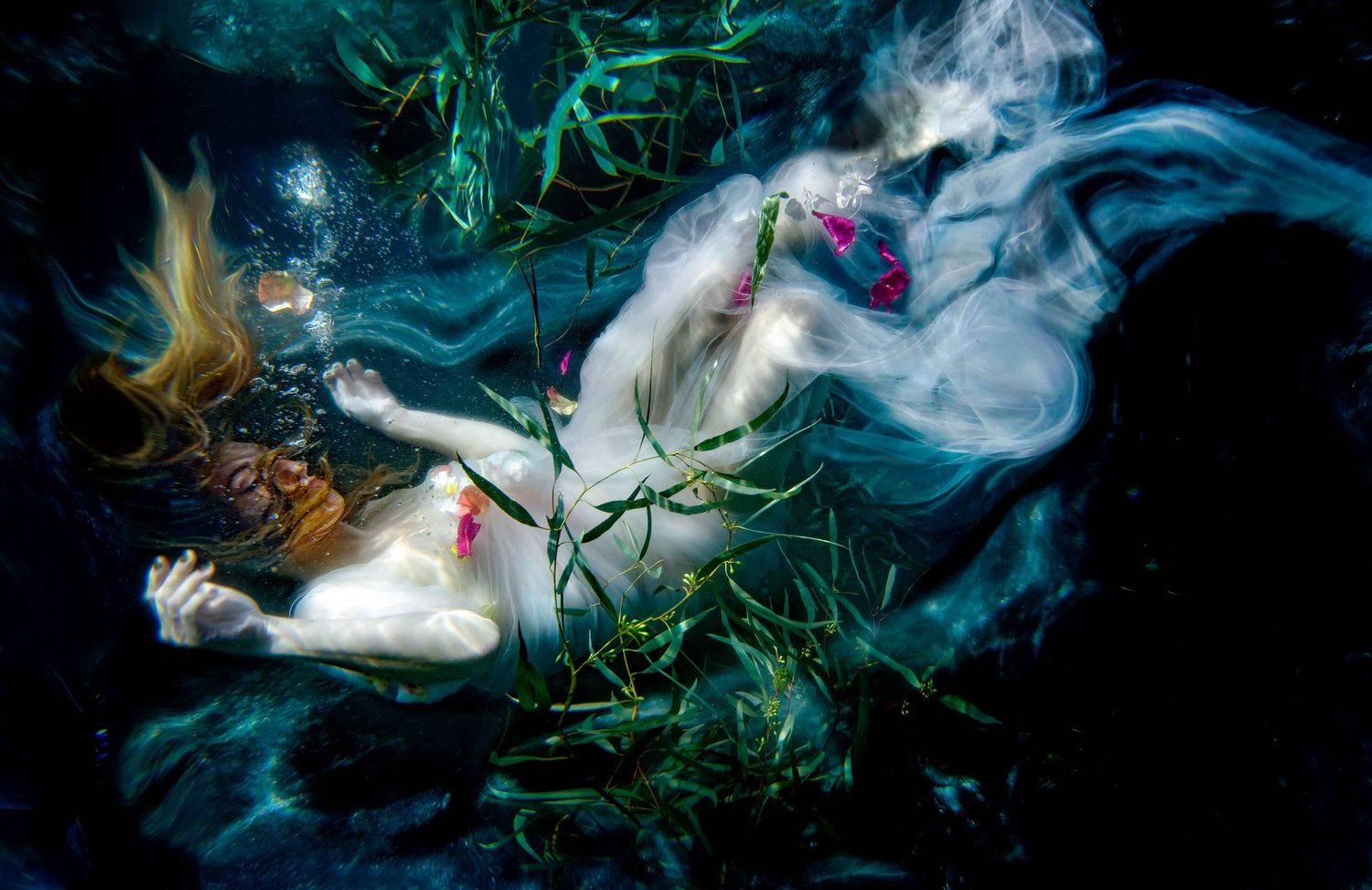Ethereal underwater photography featuring floating fabric and bubbles in dark aqua tones.