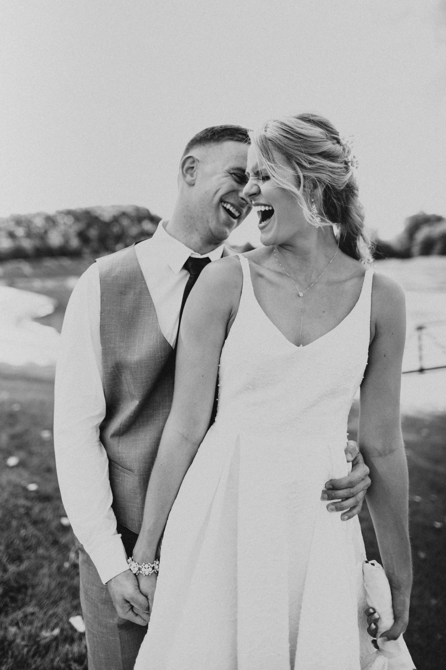A couple in white outfits shares an intimate black and white moment outdoors.